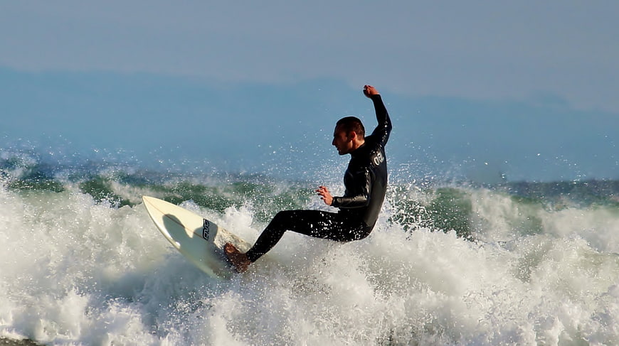 Male surfer riding a wave in a black wetsuit