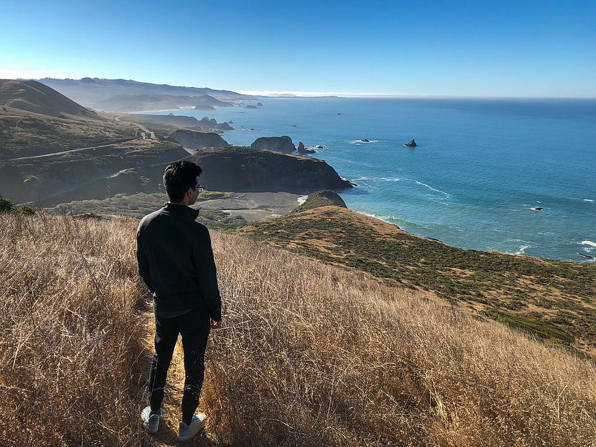Man hiking on coastal trail overlooking ocean cliffs