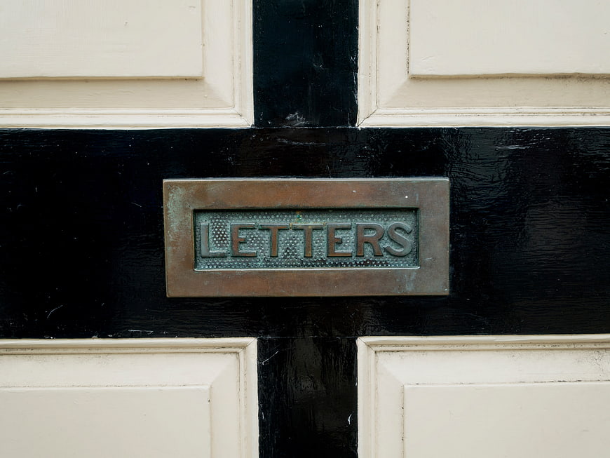 Vintage brass letters mail slot on black and white door