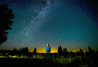 Man standing in field under Milky Way night sky