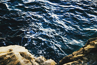 Deep Blue Ocean Waves Crashing Against Rocky Coastline