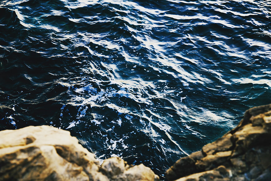 Deep Blue Ocean Waves Crashing Against Rocky Coastline