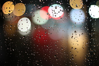 Raindrops on glass with colorful bokeh lights background