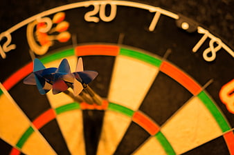 Close-up of three darts hitting the triple 20 section of a dartboard