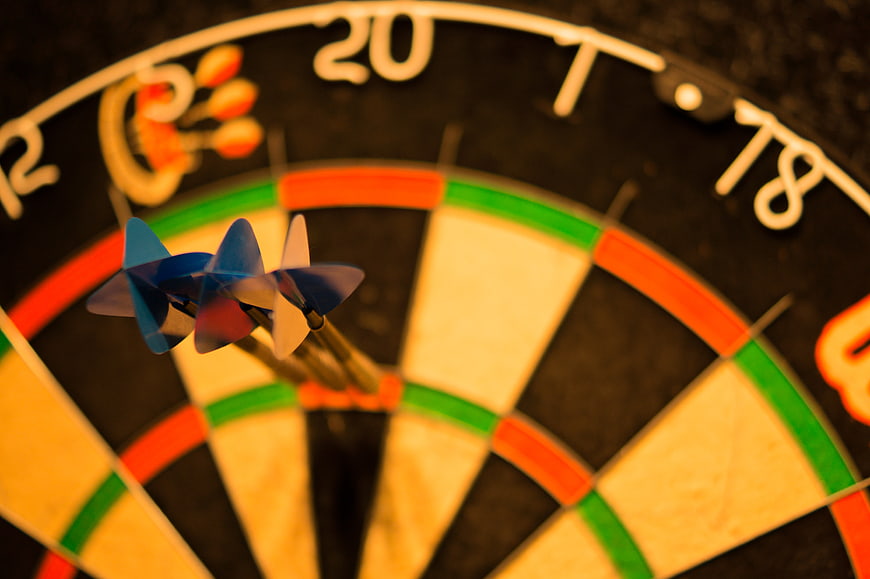 Close-up of three darts hitting the triple 20 section of a dartboard