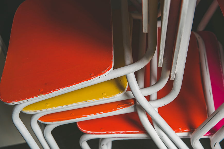 Stack of colorful vintage metal chairs with white frames