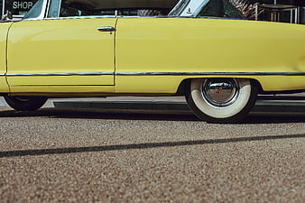 Side view of a vintage yellow classic car with whitewall tires