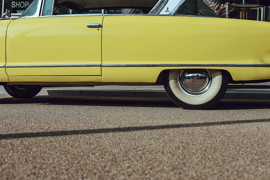 Side view of a vintage yellow classic car with whitewall tires