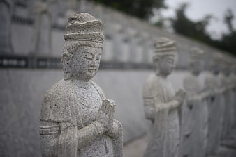 Row of gray stone Guanyin statues in a serene Asian temple setting