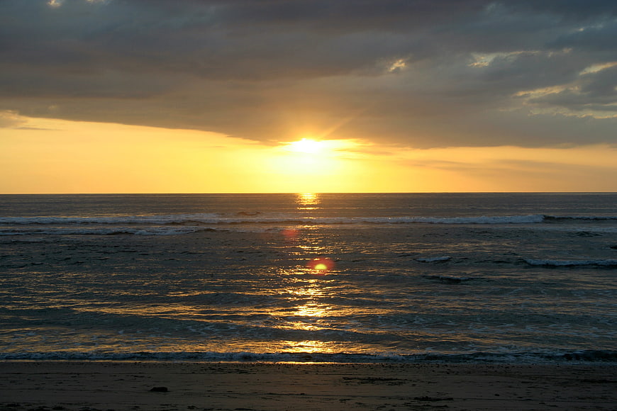 Golden Sunset Over Ocean Waves on Sandy Beach