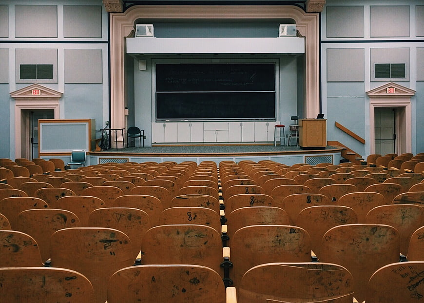 Empty Lecture Hall With Rows Of Worn Wooden Chairs