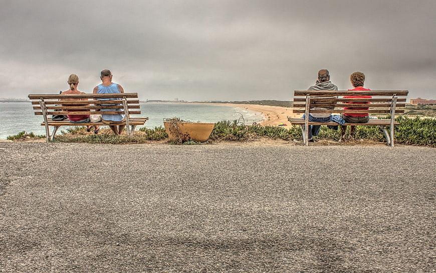 Two Couples Sitting on Benches Overlooking Beach