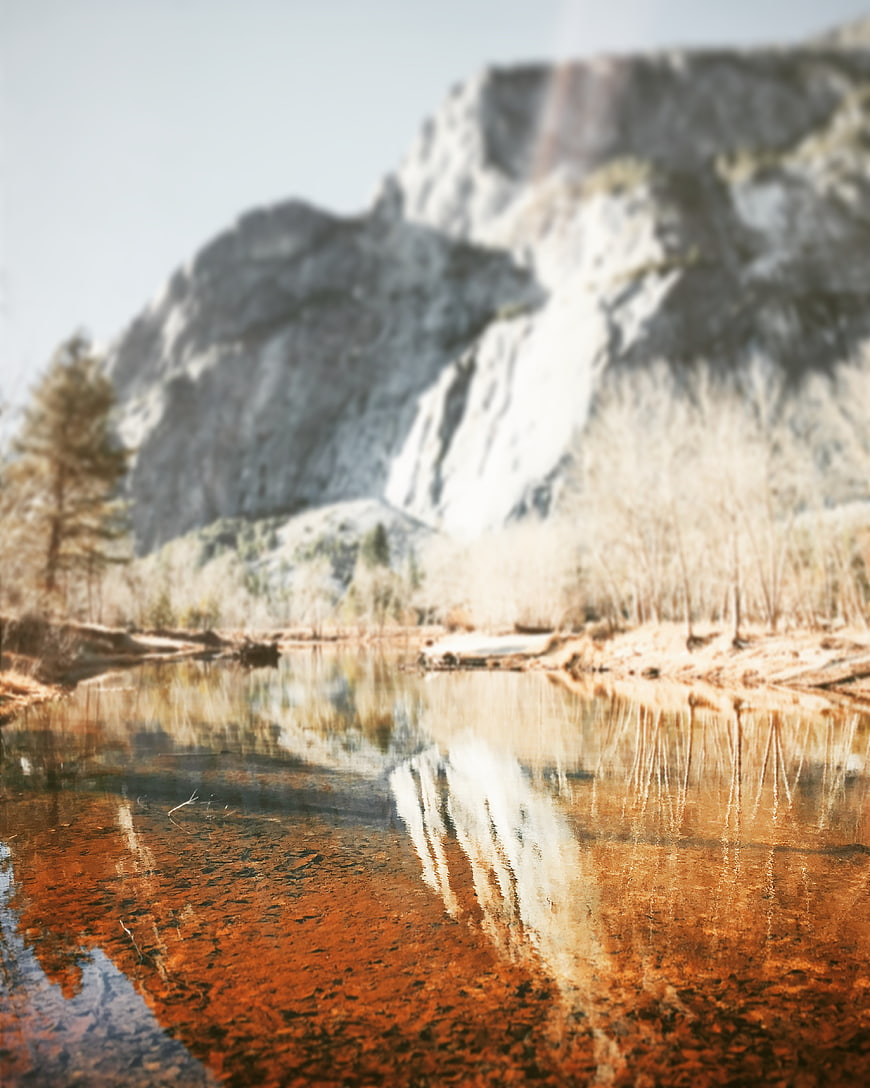 Blurred Mountain Landscape with Rust-Colored River Reflection