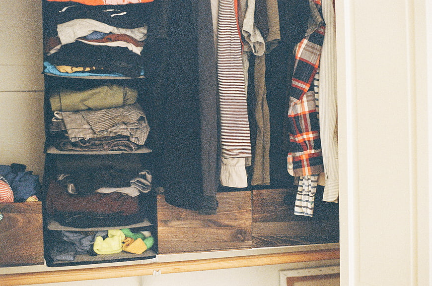 Organized closet interior with hanging shirts and folded clothes