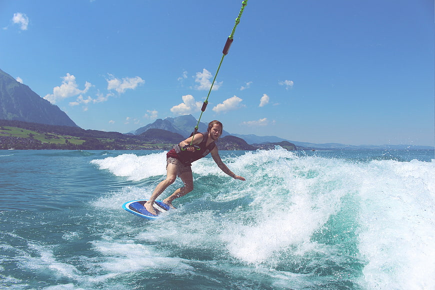 Man wakeboarding on a lake with mountains in background