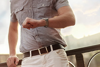 Man Checking Wristwatch on Balcony at Sunset