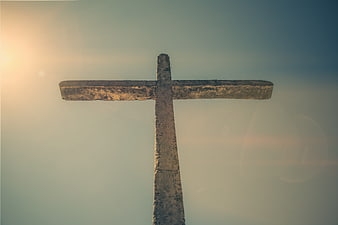 Weathered Stone Cross Silhouette Against Blue Sky