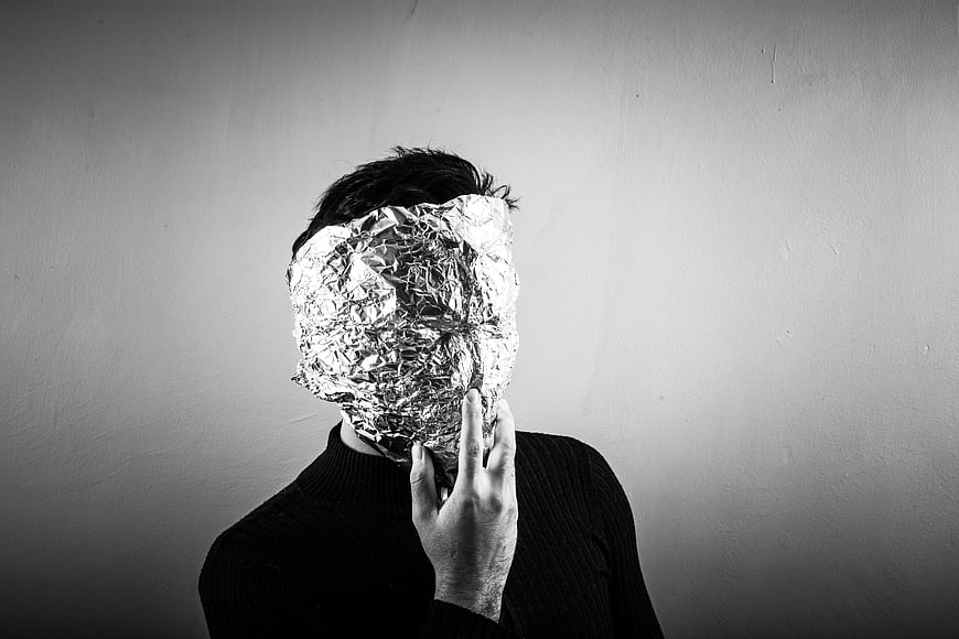 Person with face covered in crumpled aluminum foil mask