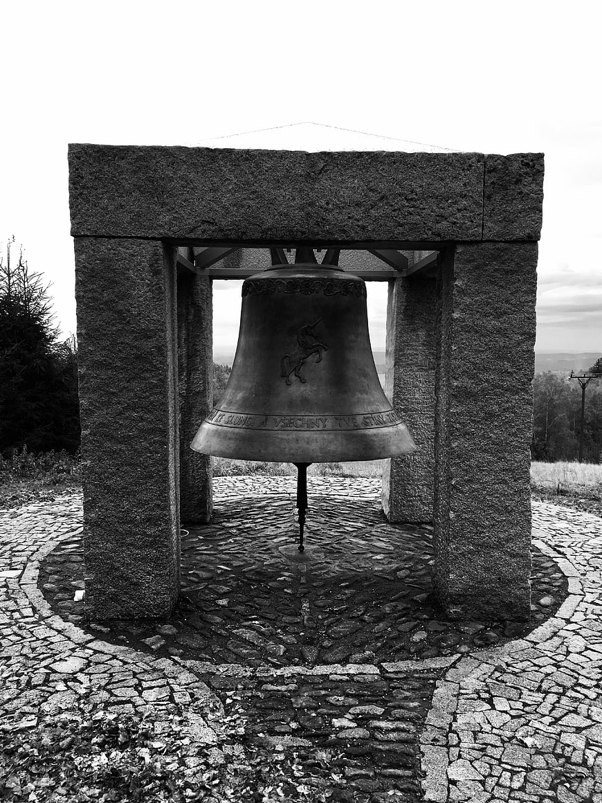 Black and white photo of a large bell in a stone structure