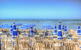 Blue and white striped umbrellas on a sunny Mediterranean beach