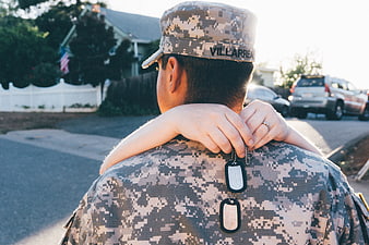 Military Soldier With Child On Shoulders In Suburban Neighborhood