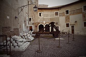 Ancient Roman Catapult and Stone Balls in Cobblestone Courtyard