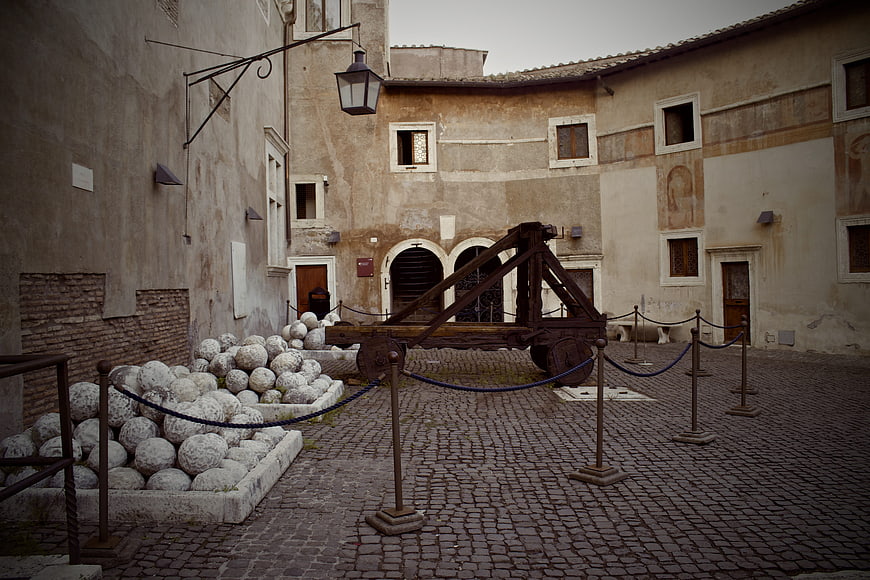 Ancient Roman Catapult and Stone Balls in Cobblestone Courtyard
