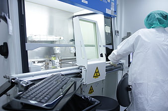 Scientist in protective suit operating laboratory equipment with radiation warning