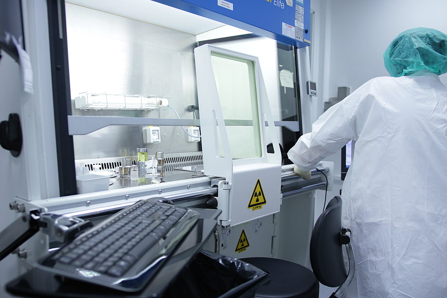 Scientist in protective suit operating laboratory equipment with radiation warning