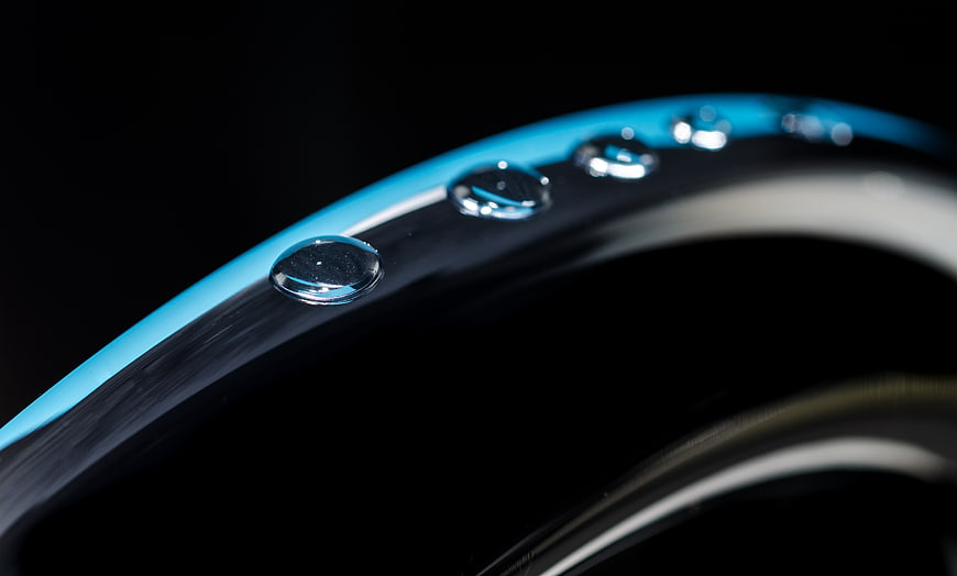 Macro shot of water droplets on a sleek blue faucet
