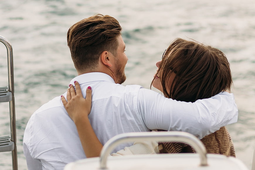 Romantic couple embracing on a yacht deck with ocean background