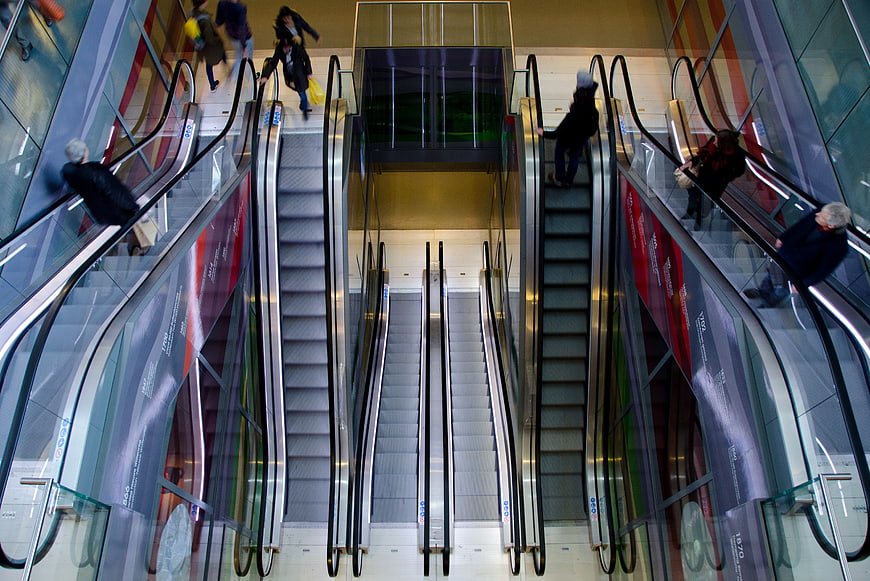 Symmetrical View of People Riding Escalators in Modern Mall