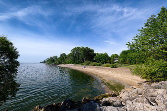 Serene Lake Shoreline with Sandy Beach and Blue Sky