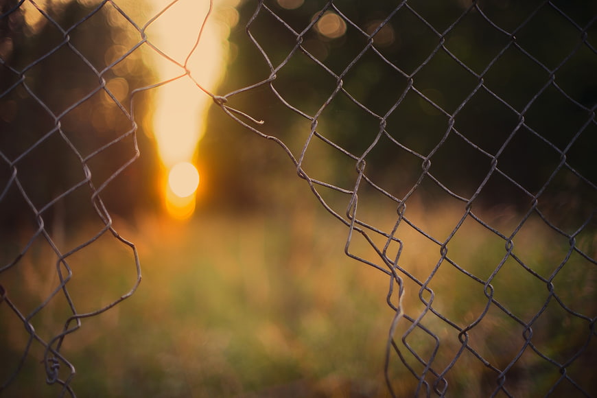 Broken Chain Link Fence with Golden Sunset Bokeh Background