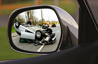 Overturned car crash seen in side mirror reflection