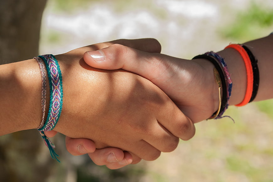 Close-up of two hands holding with colorful friendship bracelets