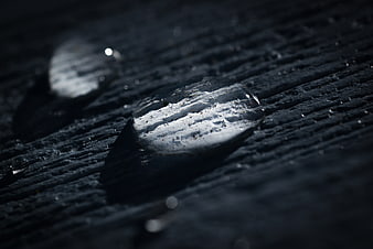Macro water droplet on dark textured wood surface