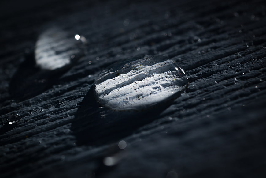 Macro water droplet on dark textured wood surface