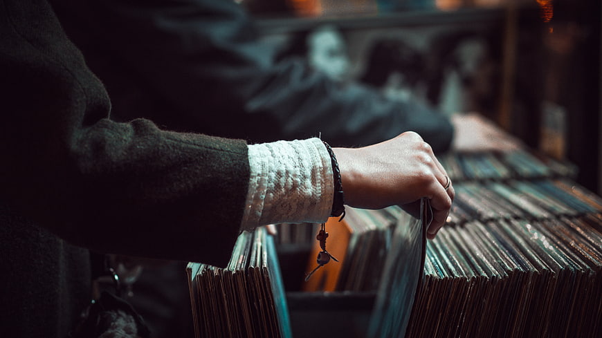 Hand browsing vinyl records in a vintage music store
