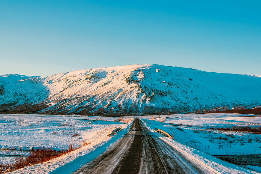 Snowy Road Leading to Mountain at Sunset