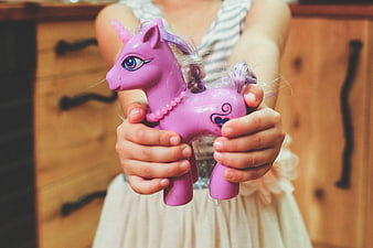 Child holding purple unicorn toy close up