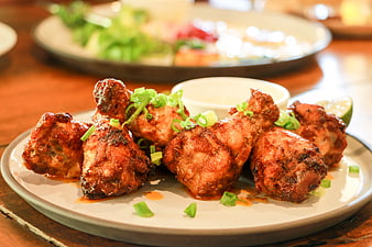 Grilled Chicken Wings with Green Onion Garnish on Plate