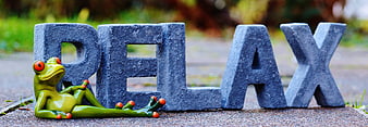 Green frog figurine relaxing next to stone letters spelling RELAX