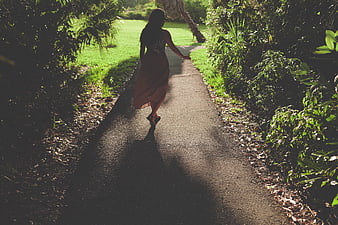 Woman in Dress Walking Down Shaded Garden Path