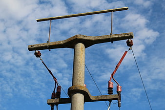 Concrete utility pole with insulators against blue sky