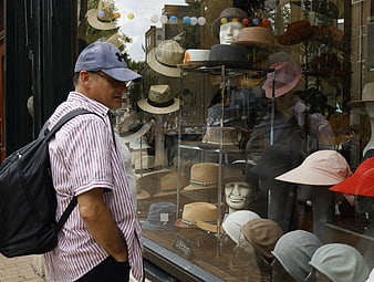 Senior man looking at hats in shop window display