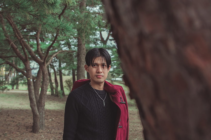 Portrait of Young Man in Red Coat in Pine Forest