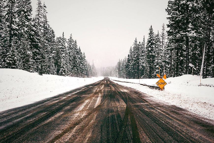 Snowy Forest Road with Bump Sign in Winter