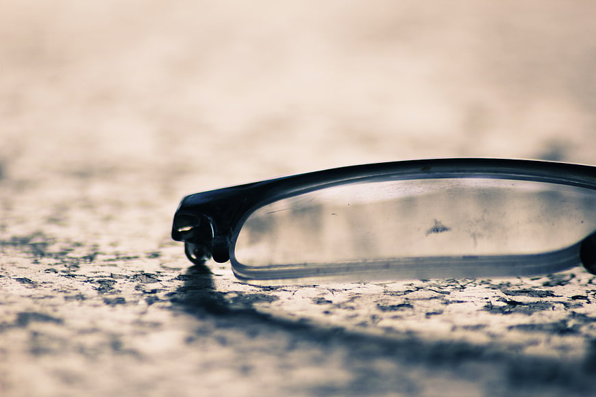 Close-up of black eyeglasses on textured concrete surface