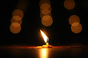 Single lit candle flame with bokeh background